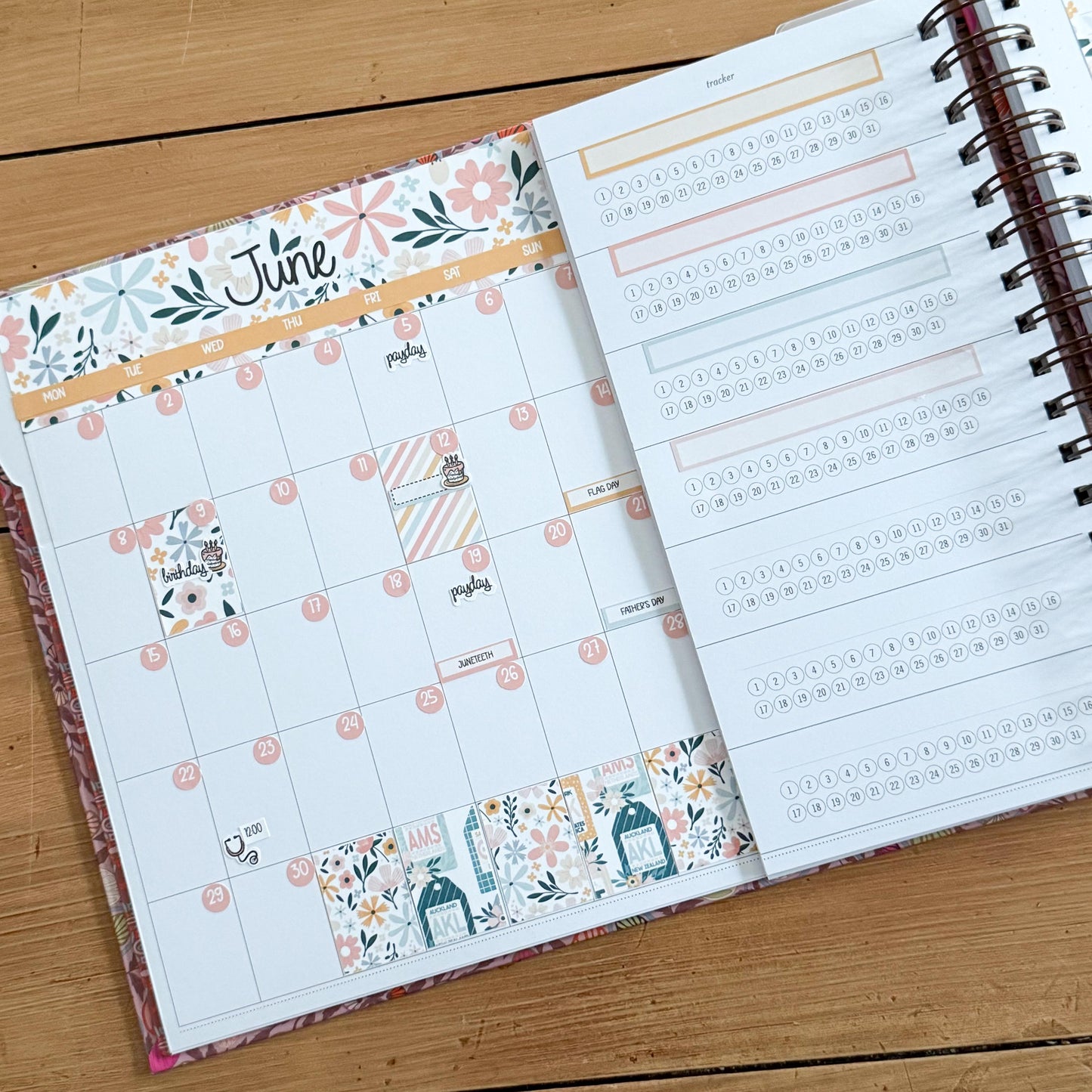 a calendar and a notebook with a floral pattern, both placed on a wooden surface.