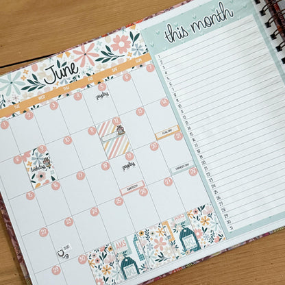 a colorful and detailed calendar for the month of June, with a list of days and events. The calendar is open and placed on a wooden surface.